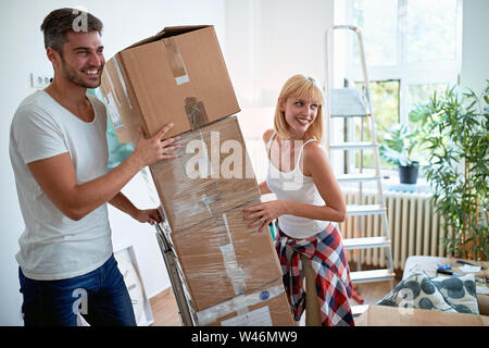 Giovane uomo sorridente e donna traslocare in una nuova casa. Foto Stock