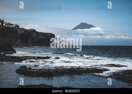 Il monte Vulcano Pico pendio occidentale vista dal mare con vertice di nuvole, visto dall'isola di Faial nelle Azzorre, Portogallo. Foto Stock