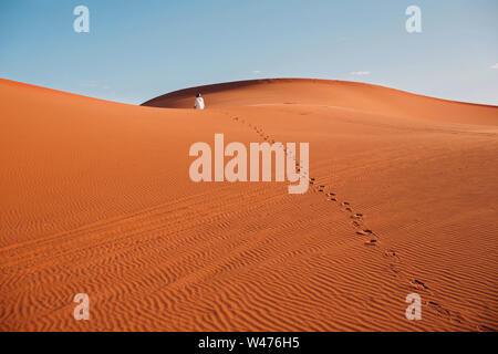 L'uomo cammina attraverso il deserto. Orme sulle dune. Foto Stock