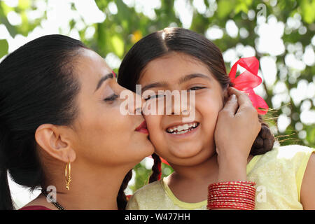 Donna indiana baciare la figlia Foto Stock