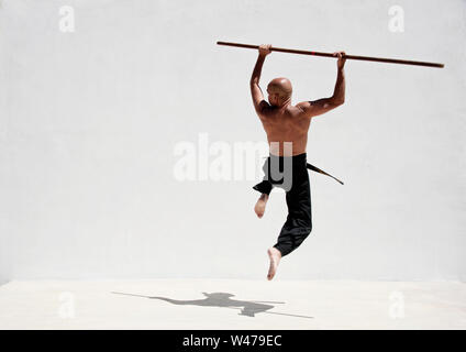 La cintura nera uomo praticanti di arti marziali con un lungo bastone. Foto Stock