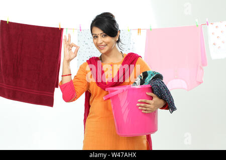 Woman drying clothes and showing ok sign Stock Photo