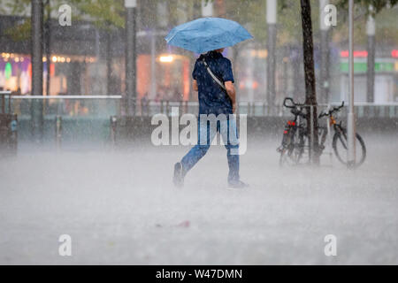 Hannover, Germania. Il 20 luglio, 2019. Durante un temporale, un uomo cammina con heavy rain oltre il Kröpcke, una piazza centrale nel centro della citta'. Credito: Moritz Frankenberg/dpa/Alamy Live News Foto Stock