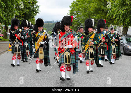 Tomintoul, Scozia. Il 20 luglio 2019 uno dei più importanti giochi delle Highland Gathering iniziò con la tradizionale sfilata delle locali bande di cornamuse attraverso la cittadina di Tomintoul e ha ringraziato la gente del posto a diverse fermate lungo la strada che hanno fornito una DRAM di locale lo scotch whisky per ogni membro della band. Nonostante la pioggia pesante, i giochi hanno continuato di intrattenimento per migliaia di spettatori compresi molti turisti provenienti da paesi stranieri Foto Stock