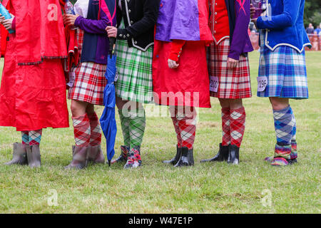 Tomintoul, Scozia. Il 20 luglio 2019 uno dei più importanti giochi delle Highland Gathering iniziò con la tradizionale sfilata delle locali bande di cornamuse attraverso la cittadina di Tomintoul e ha ringraziato la gente del posto a diverse fermate lungo la strada che hanno fornito una DRAM di locale lo scotch whisky per ogni membro della band. Nonostante la pioggia pesante, i giochi hanno continuato di intrattenimento per migliaia di spettatori compresi molti turisti provenienti da paesi stranieri Foto Stock