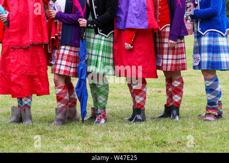 Tomintoul, Scozia. Il 20 luglio 2019 uno dei più importanti giochi delle Highland Gathering iniziò con la tradizionale sfilata delle locali bande di cornamuse attraverso la cittadina di Tomintoul e ha ringraziato la gente del posto a diverse fermate lungo la strada che hanno fornito una DRAM di locale lo scotch whisky per ogni membro della band. Nonostante la pioggia pesante, i giochi hanno continuato di intrattenimento per migliaia di spettatori compresi molti turisti provenienti da paesi stranieri Foto Stock