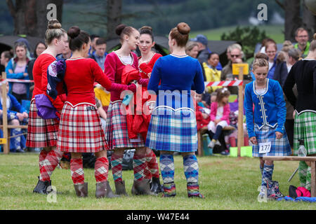 Tomintoul, Scozia. Il 20 luglio 2019 uno dei più importanti giochi delle Highland Gathering iniziò con la tradizionale sfilata delle locali bande di cornamuse attraverso la cittadina di Tomintoul e ha ringraziato la gente del posto a diverse fermate lungo la strada che hanno fornito una DRAM di locale lo scotch whisky per ogni membro della band. Nonostante la pioggia pesante, i giochi hanno continuato di intrattenimento per migliaia di spettatori compresi molti turisti provenienti da paesi stranieri Foto Stock