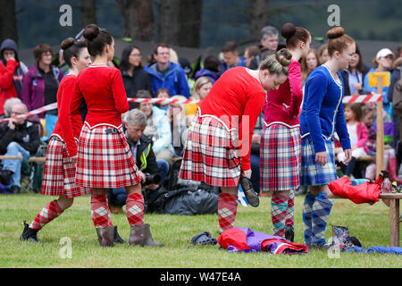 Tomintoul, Scozia. Il 20 luglio 2019 uno dei più importanti giochi delle Highland Gathering iniziò con la tradizionale sfilata delle locali bande di cornamuse attraverso la cittadina di Tomintoul e ha ringraziato la gente del posto a diverse fermate lungo la strada che hanno fornito una DRAM di locale lo scotch whisky per ogni membro della band. Nonostante la pioggia pesante, i giochi hanno continuato di intrattenimento per migliaia di spettatori compresi molti turisti provenienti da paesi stranieri Foto Stock