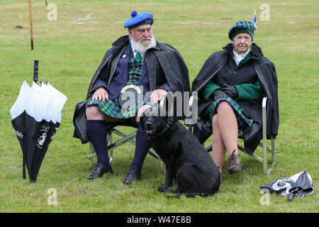 Tomintoul, Scozia. Il 20 luglio 2019 uno dei più importanti giochi delle Highland Gathering iniziò con la tradizionale sfilata delle locali bande di cornamuse attraverso la cittadina di Tomintoul e ha ringraziato la gente del posto a diverse fermate lungo la strada che hanno fornito una DRAM di locale lo scotch whisky per ogni membro della band. Nonostante la pioggia pesante, i giochi hanno continuato di intrattenimento per migliaia di spettatori compresi molti turisti provenienti da paesi stranieri Foto Stock