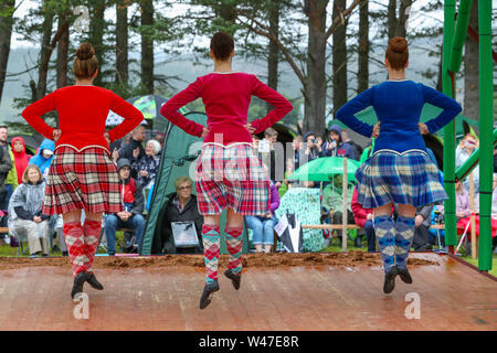 Tomintoul, Scozia. Il 20 luglio 2019 uno dei più importanti giochi delle Highland Gathering iniziò con la tradizionale sfilata delle locali bande di cornamuse attraverso la cittadina di Tomintoul e ha ringraziato la gente del posto a diverse fermate lungo la strada che hanno fornito una DRAM di locale lo scotch whisky per ogni membro della band. Nonostante la pioggia pesante, i giochi hanno continuato di intrattenimento per migliaia di spettatori compresi molti turisti provenienti da paesi stranieri Foto Stock