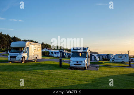 A tarda sera sun con camper e roulotte in un campeggio nel Galles del Nord Regno Unito Foto Stock