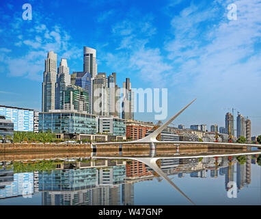 Puente de la Mujer ponte in Buenos Aires e lo skyline contro un Cielo di estate blu con poche nuvole bianche riflettono sul fiume. Foto Stock