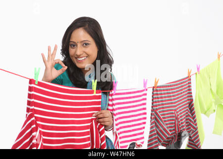 Woman drying clothes and showing ok sign Stock Photo