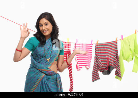 Woman drying clothes and showing ok sign Stock Photo