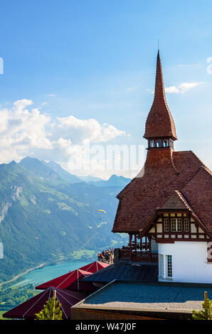 Bella top Harder Kulm in Swiss Interlaken fotografato in estate il tramonto con parapendii battenti intorno a. Il turchese del lago di Thun in background. Paesaggio alpino. Destinazione di viaggio. Foto Stock