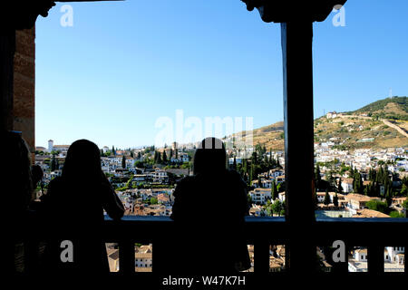 Silhouette di visitatori la visualizzazione di Granada e il quartiere Albaicin da uno dei passaggi pedonali e balconi a la Alhambra di Granada, Spagna. Foto Stock