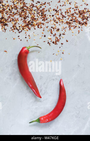 Due peperoncini piccanti sul marmo grigio sfondo, utilizzare per l'arabo salsa Harissa, georgiano sause adjika. Italiano bio peperoncino dalla Calabria Foto Stock