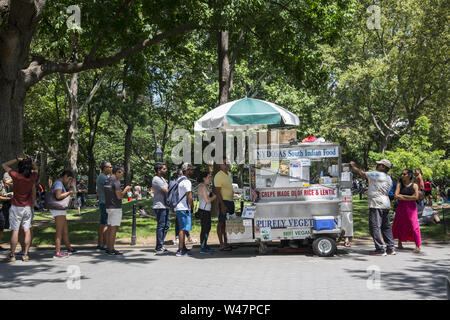 Molti Indiani e altri la linea fino a un popolare a sud il cibo indiano venditore in Washington Square Park a pranzo nel Greenwich Village di New York City. Foto Stock