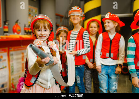 Bambini in casco e uniforme con tubo e estintore in mani giocando