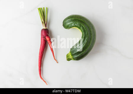 Alla moda di brutto verdura biologica la carota e la zucchina dal giardino di casa su marmo bianco tavola. vista superiore. laici piatta Foto Stock