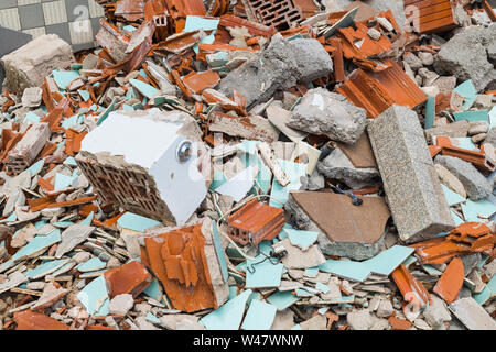 Costruzione di discarica di rifiuti. Mattoni, tegole e pezzi di cemento nel mucchio di detriti. Danneggiato e incrinato vecchio pavimento e muratura bagno da demolizione. Il disastro. Foto Stock