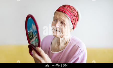 Senior Caucasiasn donna che guarda a se stessa e a specchio Foto Stock