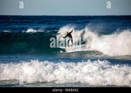 Surfista maschile in surf cavalcando le onde presso la spiaggia di Avalon a Sydney, NSW, Australia Foto Stock