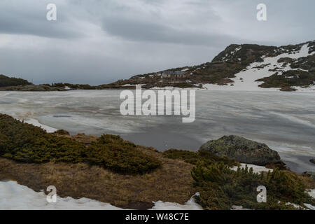 In inverno il paesaggio di montagna in Bulgaria, Ribnoto (pesce) il lago con il rifugio Sette Laghi a sfondo. Montagna Rila. Foto Stock