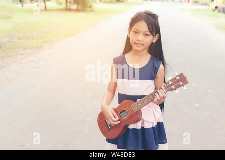 Grazioso fanciullo ragazza a suonare la chitarra. Foto Stock