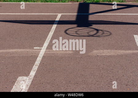 Ombra di una street basketball board con anello e net sul aspahlted sport place nella città. Copia dello spazio. Foto Stock