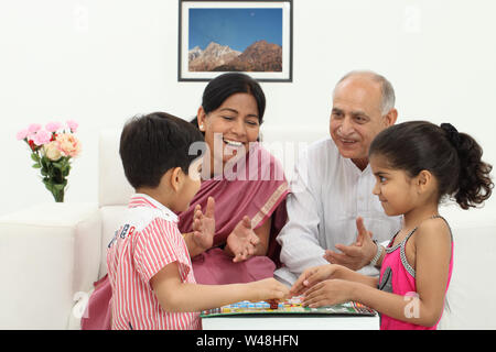 Ragazzo e ragazza che giocano a Ludo con i loro nonni Foto Stock