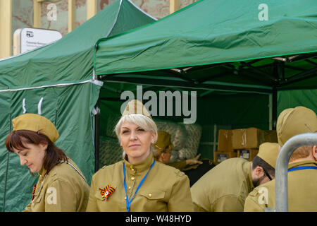 Mosca, Russia - 9 Maggio 2019: reggimento immortale processione nel giorno della vittoria. Bella donna bionda dà razioni di cibo per soldato Foto Stock