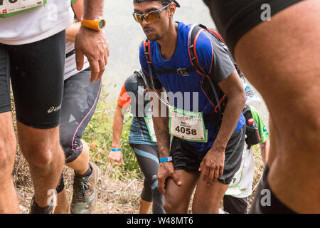 Stanco delle guide di scorrimento nel sensore pioggia, arrampicata al di fuori di un cratere sulla ripida traccia approssimativa da les deux Bras nel Cirque de Mafate durante il Grand Raid, Reunion Foto Stock