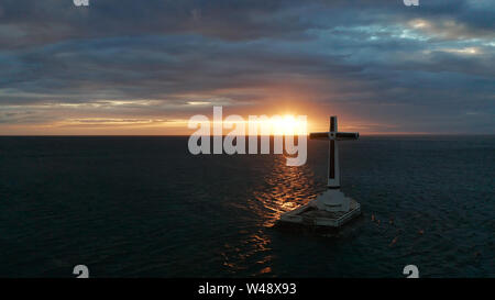 Croce cattolica nel cimitero affondata nel mare al tramonto, antenna fuco. colorato cielo durante il tramonto. Grandi crucafix segnando il sottomarino sunken cimitero, CAMIGUIN ISLAND Filippine. Foto Stock