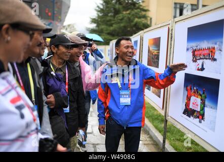 (190721) -- LHASA, luglio 21, 2019 (Xinhua) -- Zhaxi Cering (1R) introduce le sue foto al suo personale di fotografia a tema espositivo sul Monte Qomolangma a Lhasa, capitale del sud-ovest della Cina di regione autonoma del Tibet, luglio 12, 2019. Non sarebbe l'orgoglio di dire che Zhaxi Cering della fotografia di carriera iniziata su un alto: la fotografia che sparato a fama a poco più di un decennio fa è stata presa sulla parte superiore delle più alte del mondo montagna. In 2008, Zhaxi era un membro dell'arrampicata cinese team che ha portato la torcia olimpica al vertice di Mt. Qomolangma. Appena 26 anni al momento, Zhaxi h Foto Stock