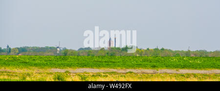 In tipico stile olandese verde paesaggio con una chiesa e mulini a vento, skyline Tholen, Zeeland, Paesi Bassi Foto Stock