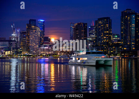 Di notte la città e il porto di riflessione con la Luna Piena riflettendo sul Victoria Harbour Docklands Melbourne Victoria Australia Foto Stock