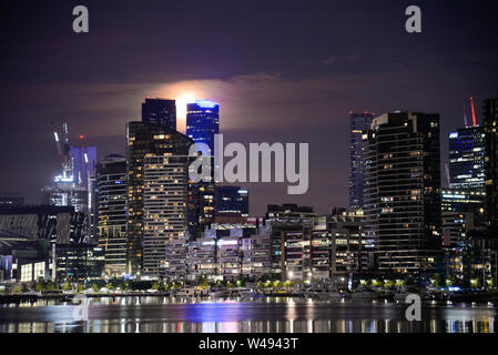 Di notte la città e il porto di riflessione con la Luna Piena riflettendo sul Victoria Harbour Docklands Melbourne Victoria Australia Foto Stock