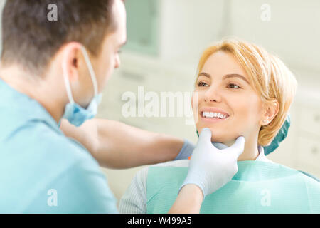 Dentista guardando i denti del paziente ragazza seduta su una sedia nella clinica dentale. Foto Stock