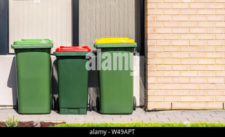 Australian garbage impennarsi in contenitori con coperchi colorati per il riciclaggio, generale e rifiuti verdi forniti dal consiglio locale Foto Stock