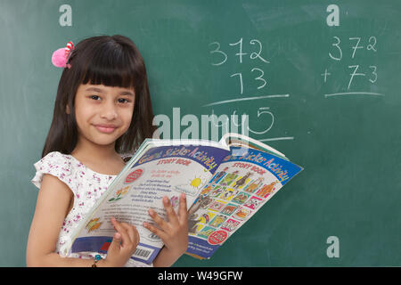 Studentessa che legge uno storybook in un'aula Foto Stock