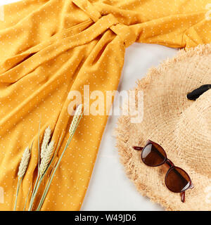 Frumento,cappello di paglia, giallo abito elegante luce su sfondo bianco. Appartamento laico, vista dall'alto, copia spazio, copyspace. autunno umore, atmosfera Foto Stock