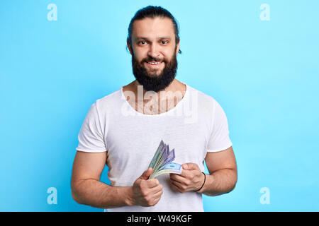 Imprenditore barbuto con denaro guardando la telecamera, prospera attività, l uomo ha vinto il denaro nella lotteria Foto Stock