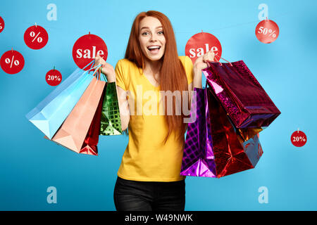 Ragazza urlando come ella ha comprato molti vestiti eleganti. I dolci della vita. allegria. shopping femmina di trasmissione via IR con piacere. isolato backgrou blu Foto Stock