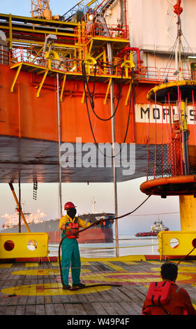 La nave l'equipaggio lavorano sul ponte durante il trasferimento piattaforma petrolifera personali per nave dal cesto di sicurezza operano tramite il gruista Foto Stock