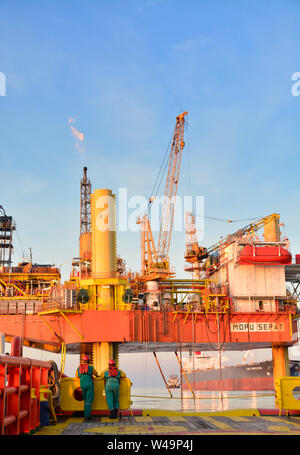 La nave l'equipaggio lavorano sul ponte durante il trasferimento piattaforma petrolifera personali per nave dal cesto di sicurezza operano tramite il gruista Foto Stock