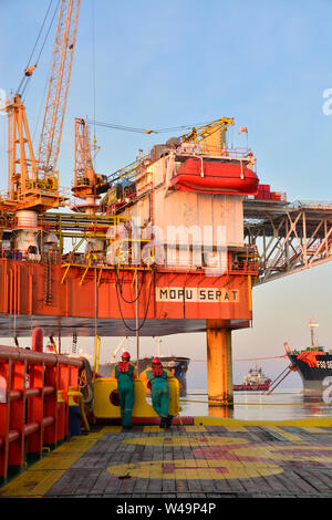 La nave l'equipaggio lavorano sul ponte durante il trasferimento piattaforma petrolifera personali per nave dal cesto di sicurezza operano tramite il gruista Foto Stock