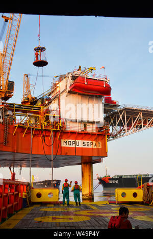 La nave l'equipaggio lavorano sul ponte durante il trasferimento piattaforma petrolifera personali per nave dal cesto di sicurezza operano tramite il gruista Foto Stock