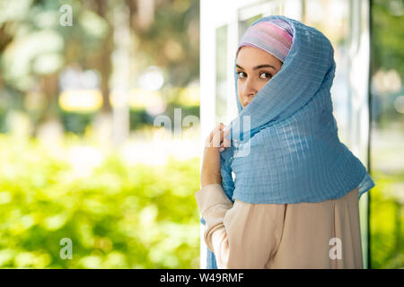 Attraente giovane donna araba in hijab guardando sopra la sua spalla Foto Stock