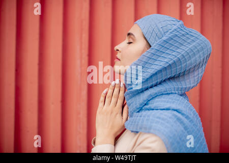 Vista laterale di Arabian religiosa in hijab pregando Foto Stock